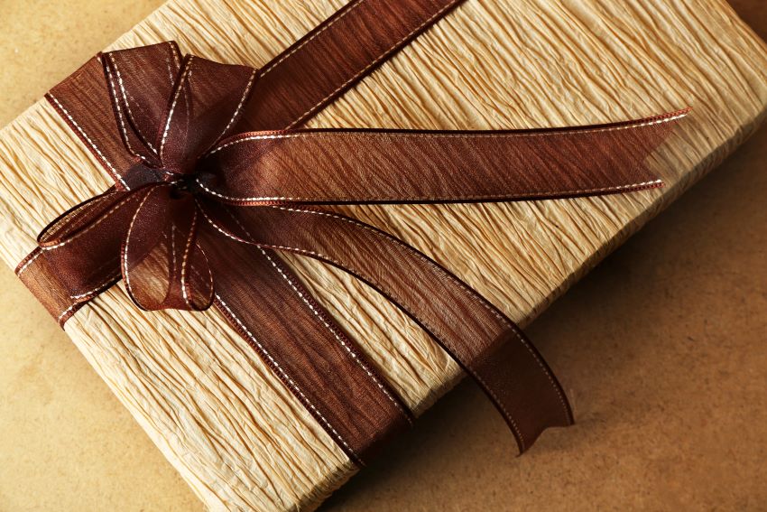 Caja de bienvenida abierta con productos promocionales personalizados como un cuaderno y un bolígrafo, mostrando el logo de